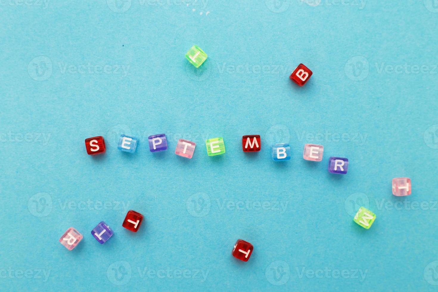 inscription September made by multicolor plastic cubes on a blue background. photo