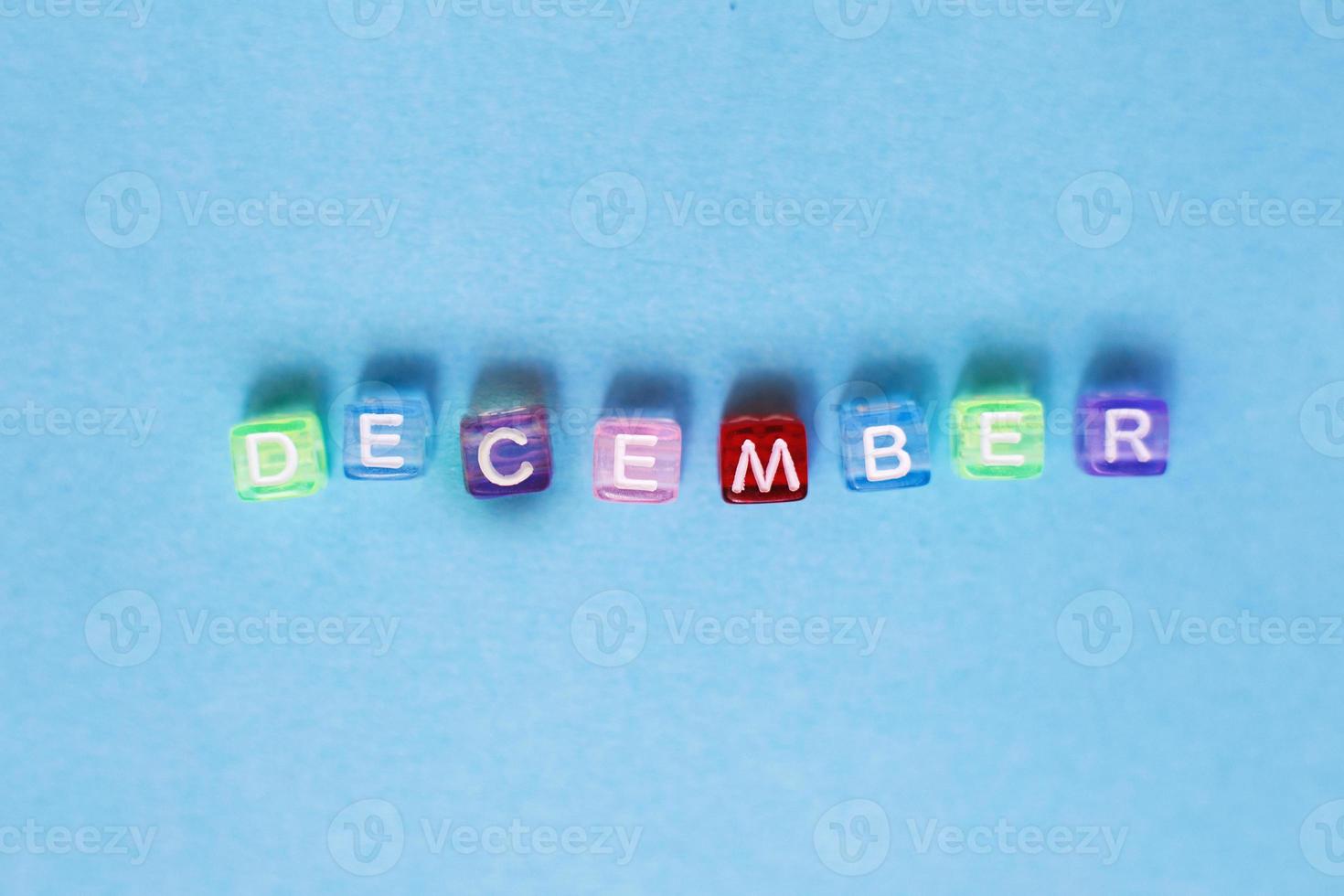 inscription december made by multicolor plastic cubes on a blue background. photo