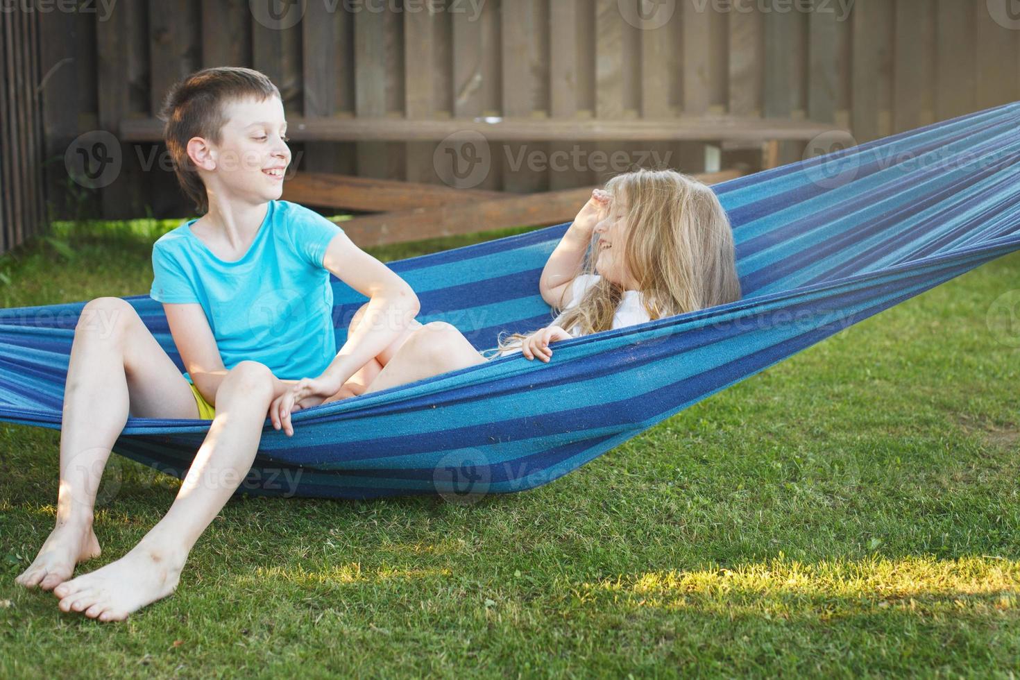 children brother and sister resting in the garden on a hammock photo