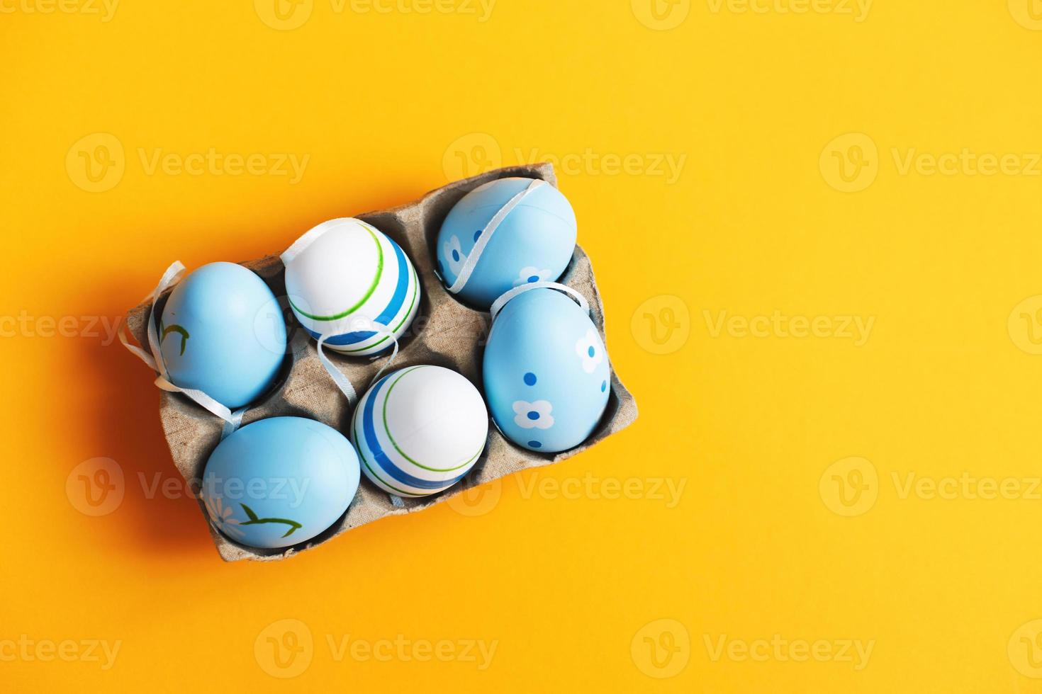 top view easter colorful handmade painted blue eggs in a box on orange background photo