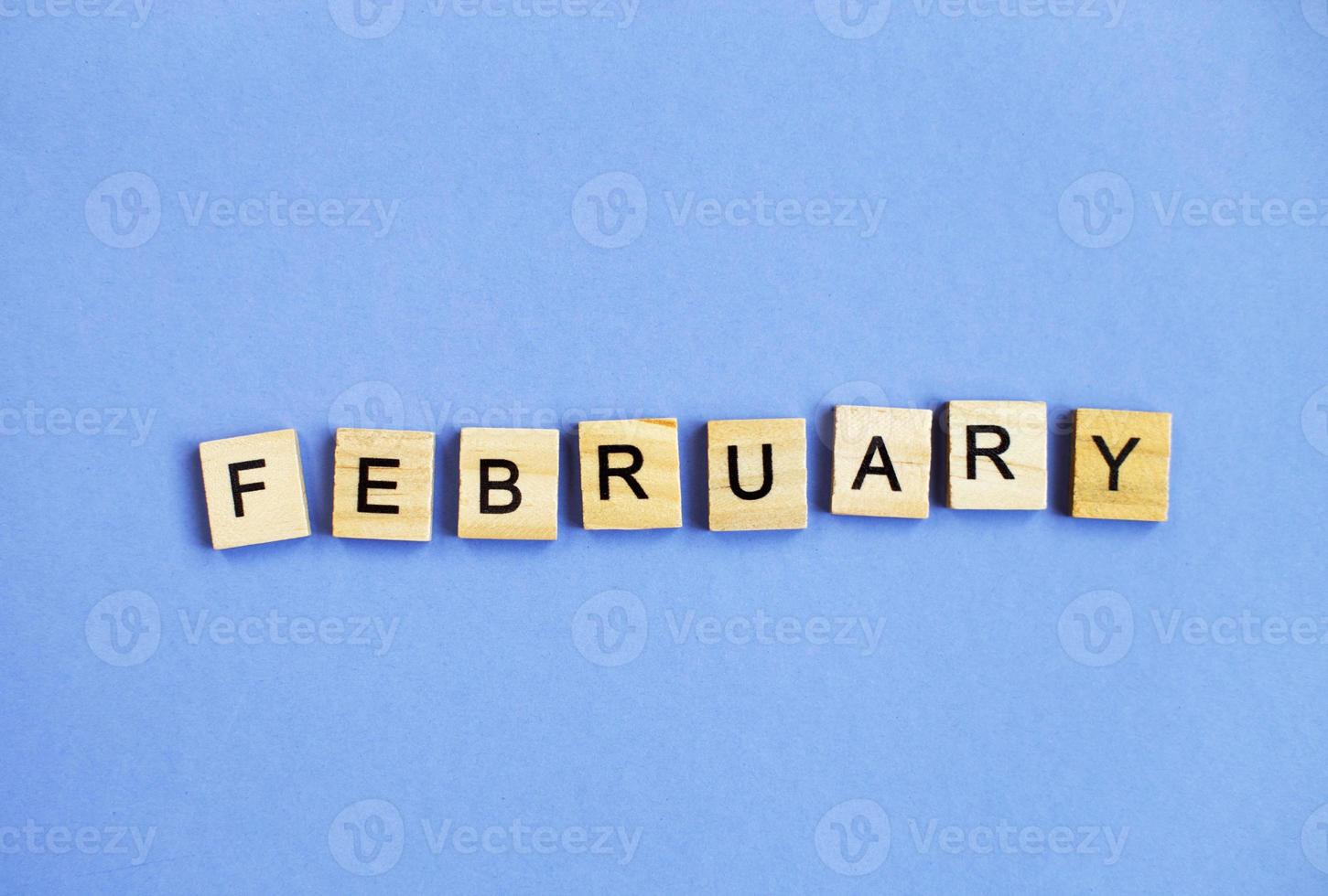 inscription February made by wooden cubes on a veri peri purple background. photo