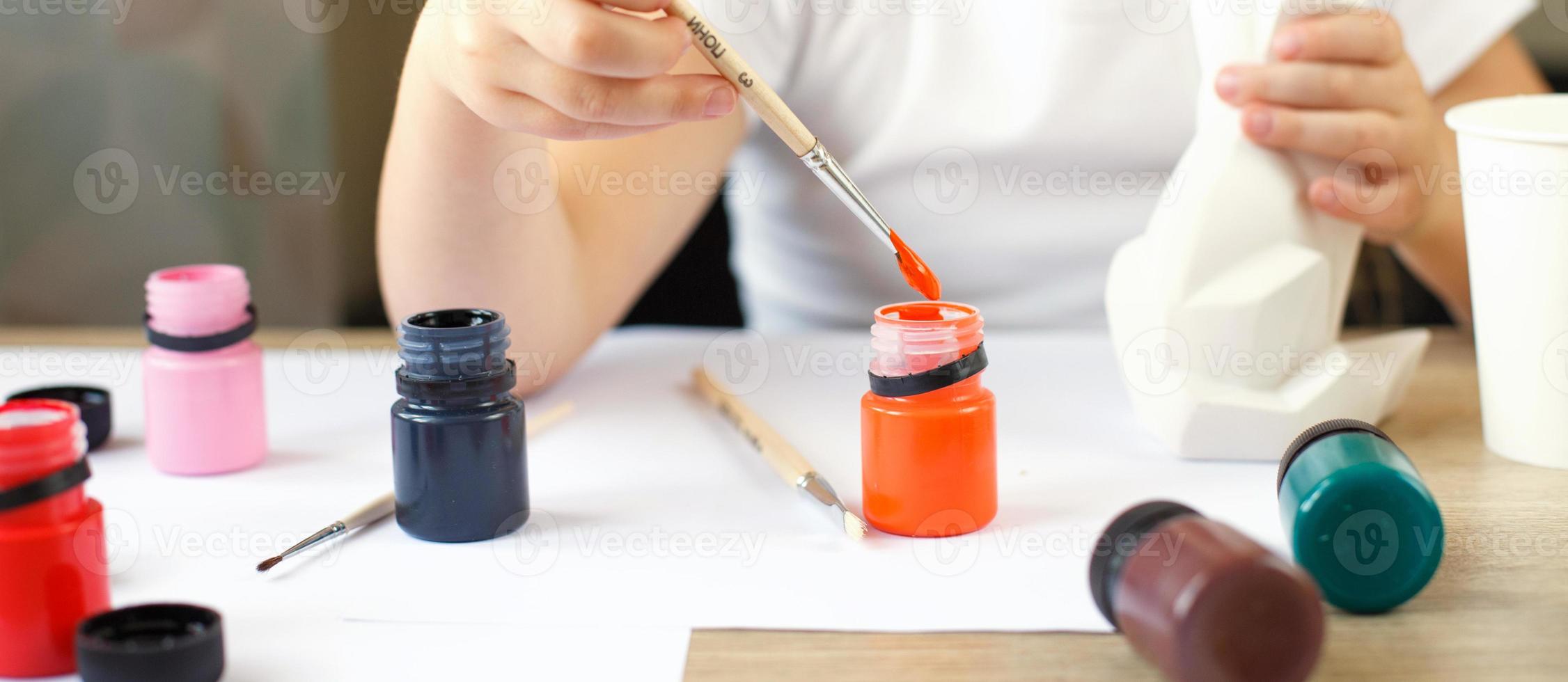 a little girl paints a toy fox made of clay. DIY concept photo