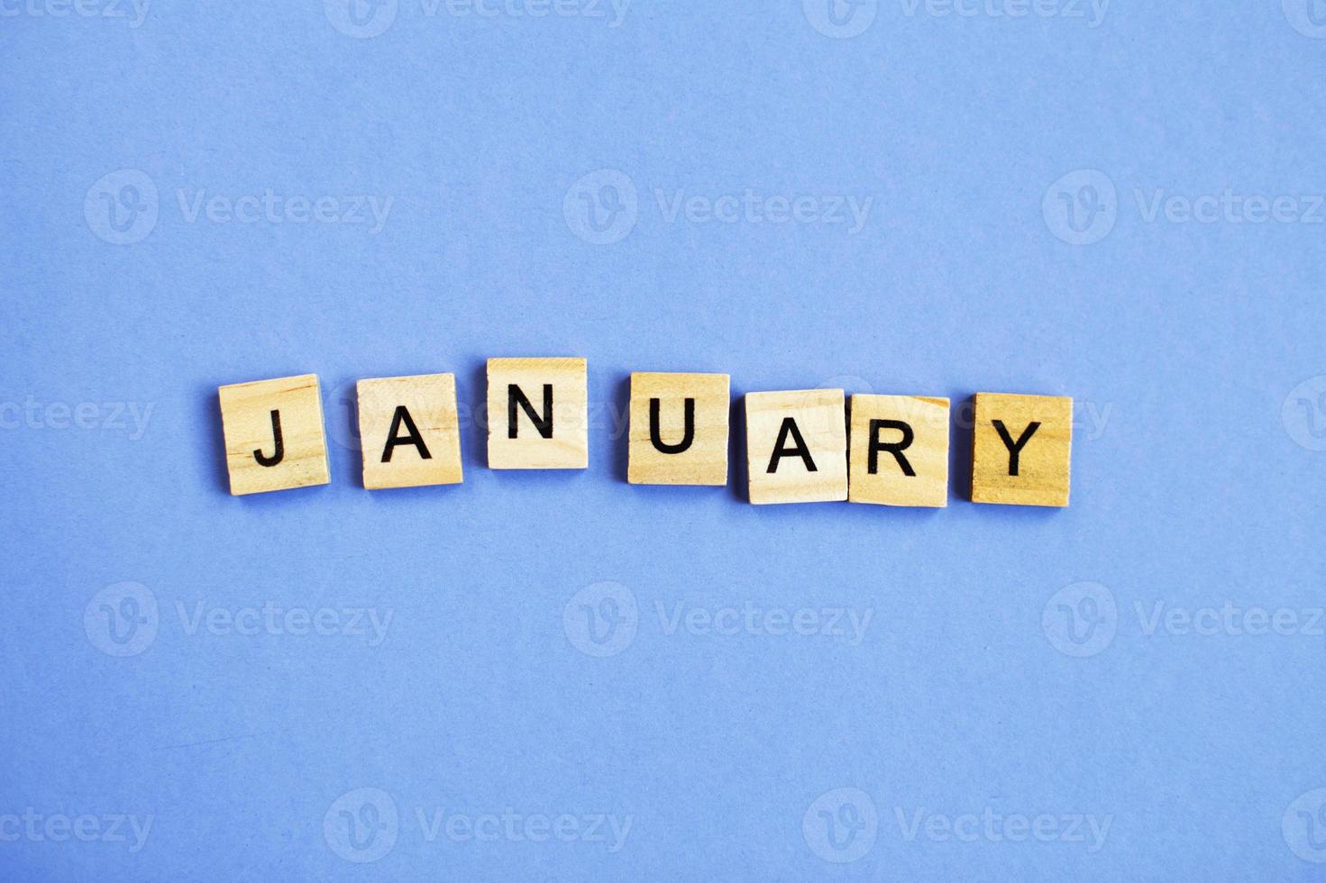 inscription January made by wooden cubes on a veri peri purple background. photo