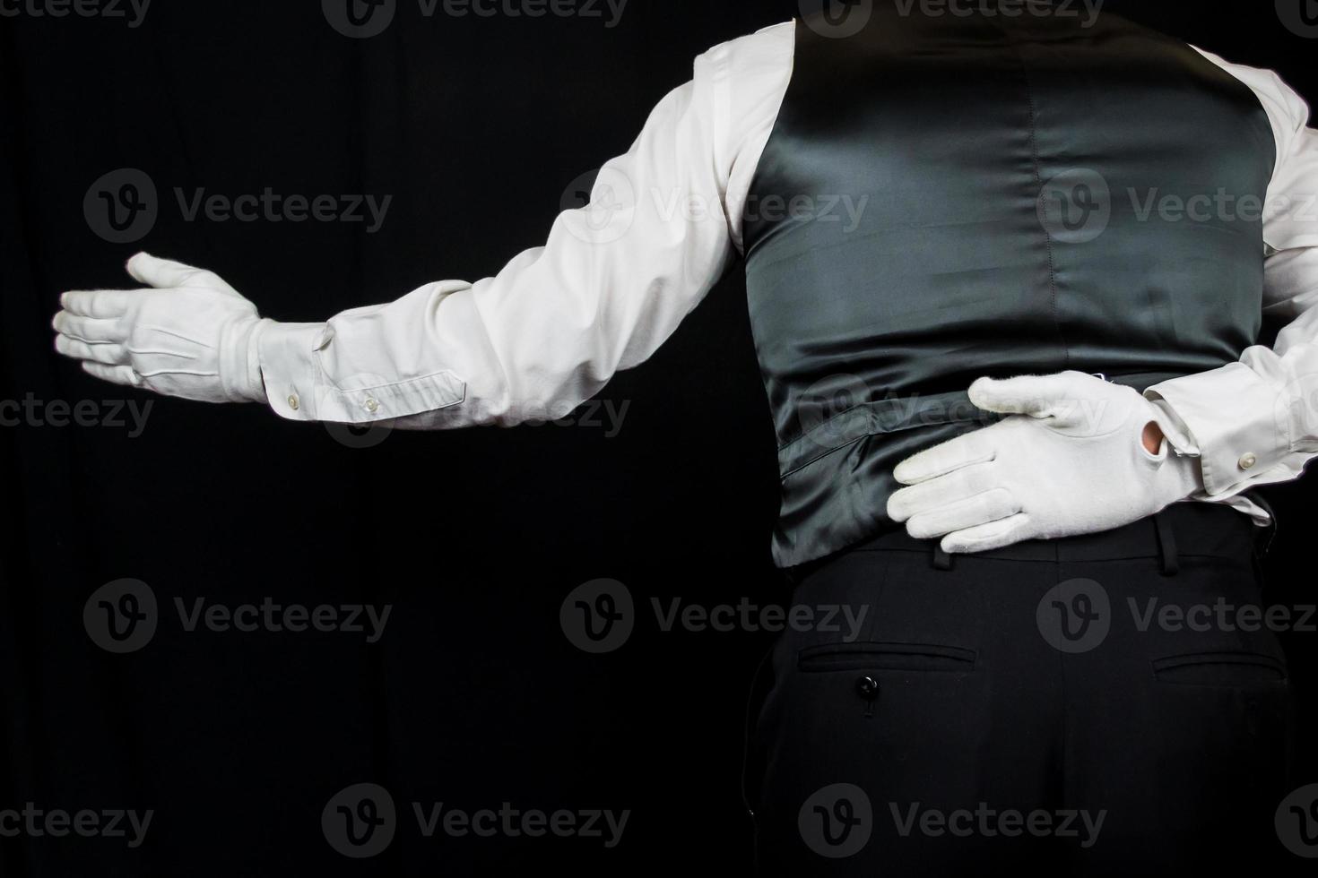 Butler or Waiter in White Gloves Bowing with Welcoming Gesture on Black Background. Concept of Service Industry and Professional Hospitality and Courtesy. photo