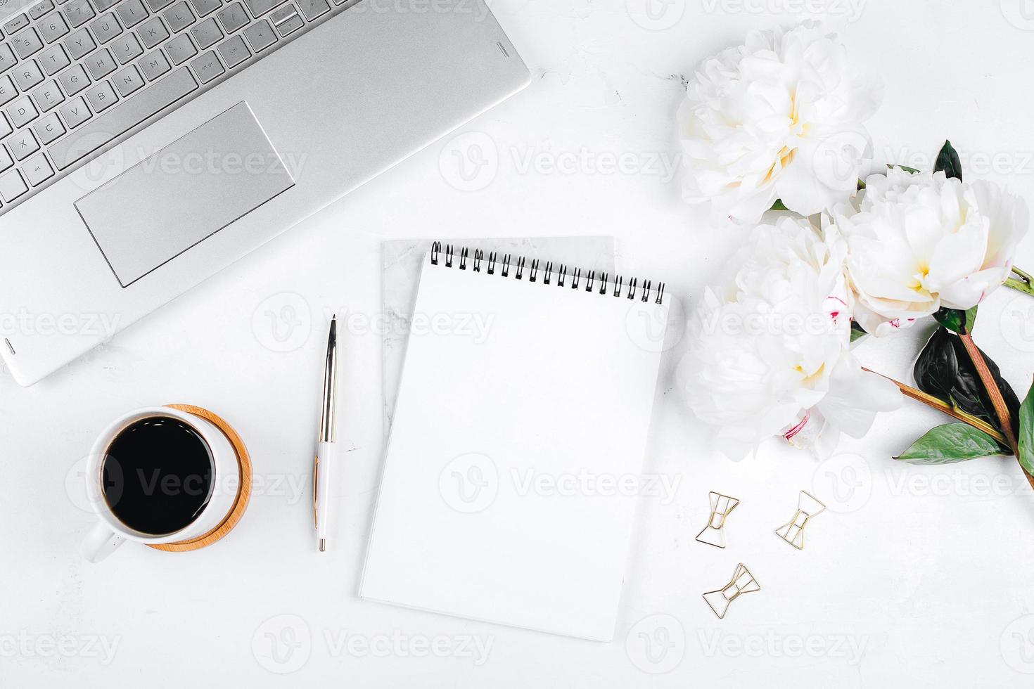 Workplace with laptop, cup of coffee, flowers peonies, pen, notebook. Flat lay, top view, mockup photo