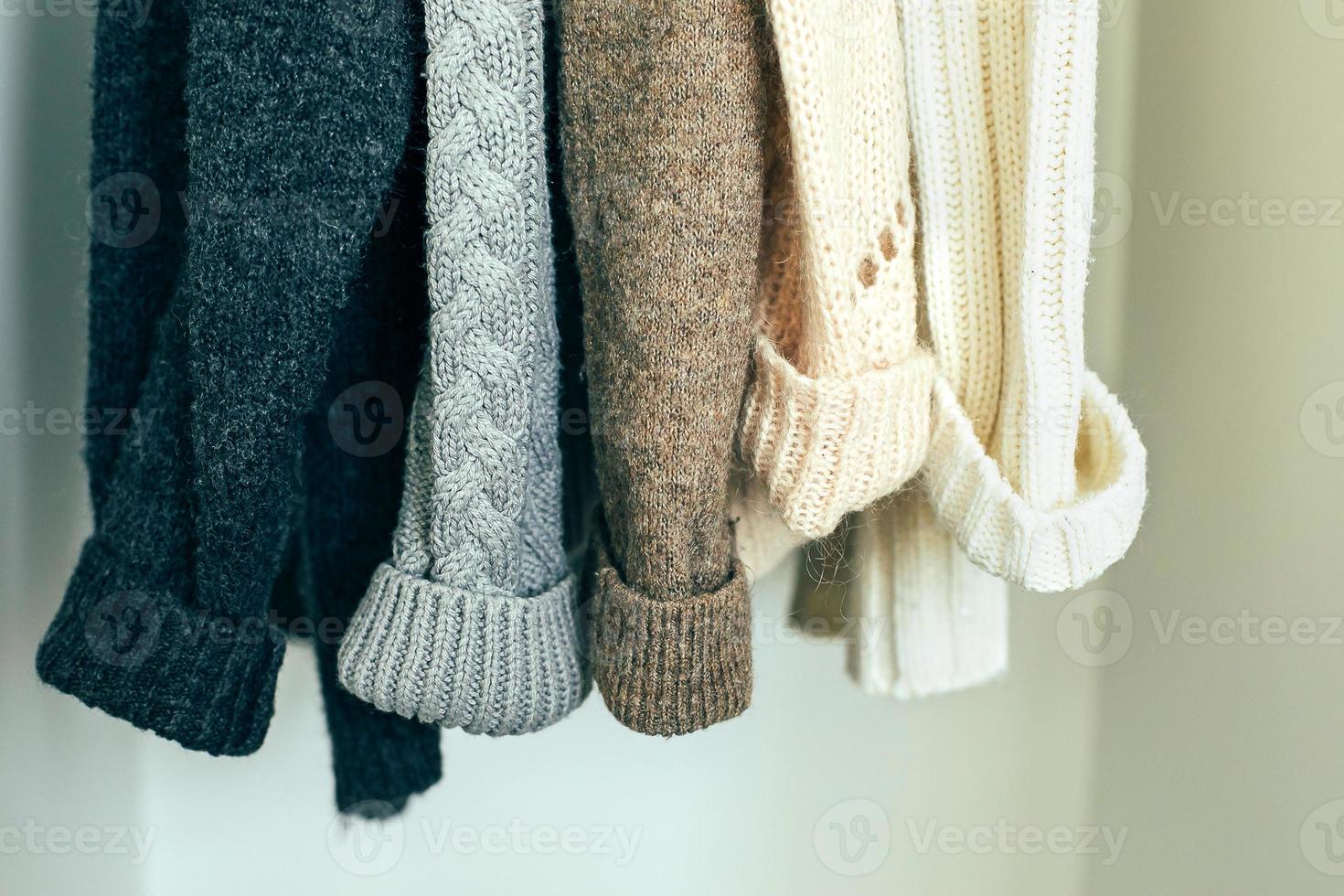 Knitted clothes sweater hanging in the closet. Cozy autumn-winter wardrobe photo