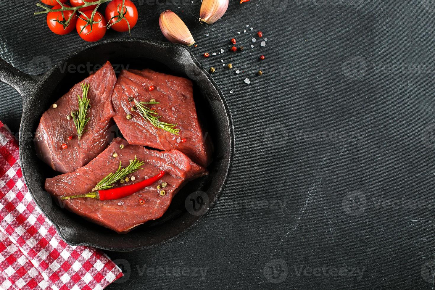Raw meat. Raw beef steak on a black board with herbs and spices. Top view, copy space photo