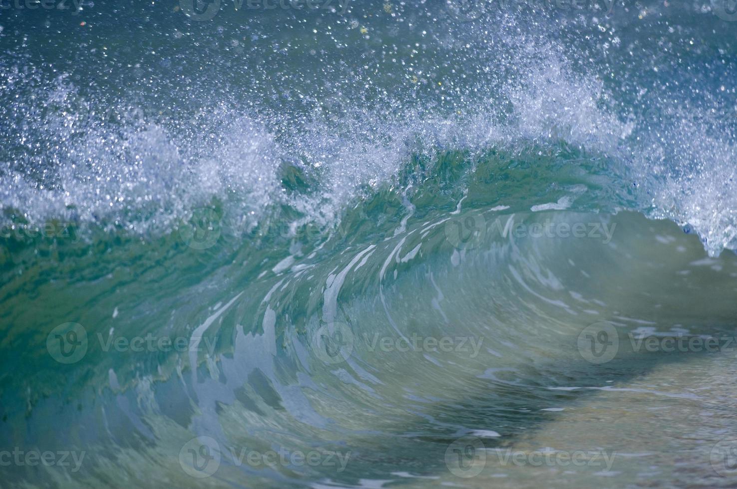 A wave smashing on the sand shore photo