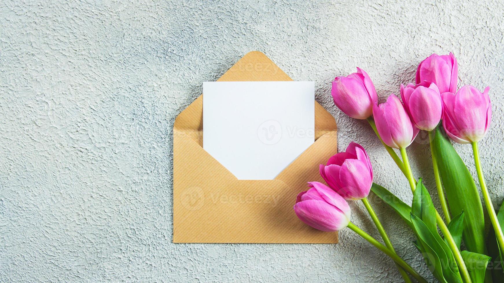 Mother's day or Woman Day Concept. Pink tulips flowers and empty card on concrete background. Greeting card for Womens or Mothers Day. Flat lay, top view, copy space. Mockup concept. Banner photo