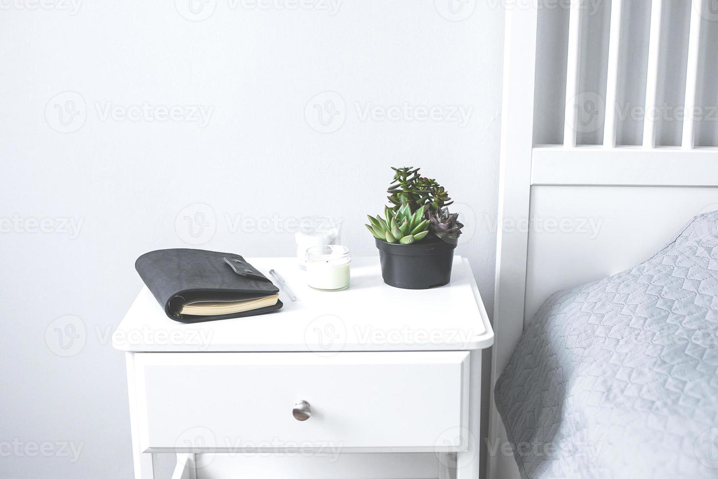 Tiny succulents, candles and black notebook on bedside table in the bedroom in scandinavian style photo