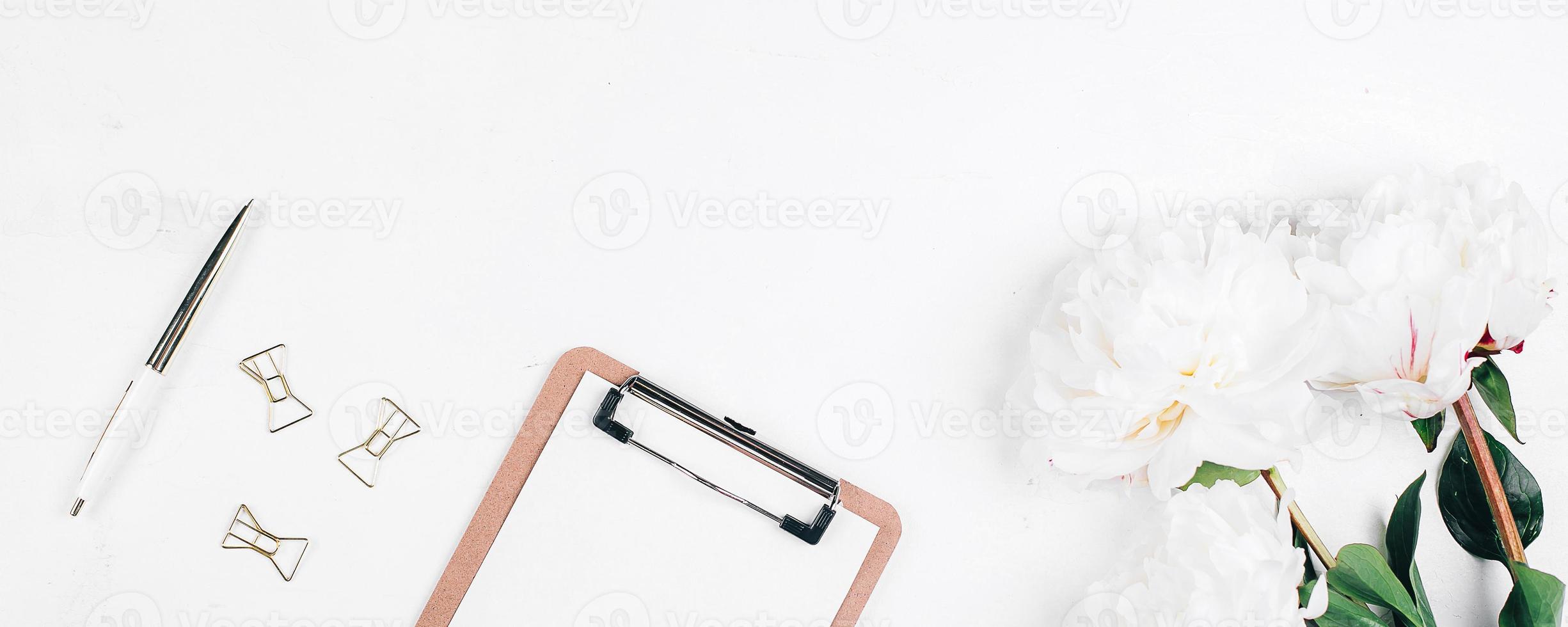 Flat lay Office table desk. Workplace with flowers peonies, clipboard and pen. mockup. Banner image photo