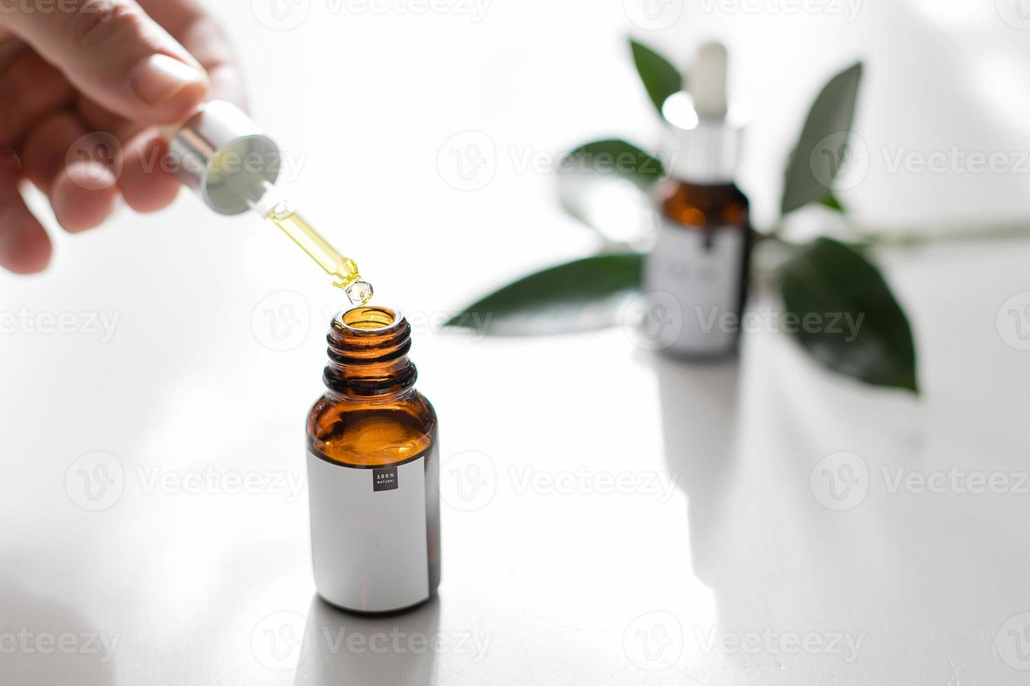 Pipette with drop of essential oil in hand. Beauty, natural cosmetics