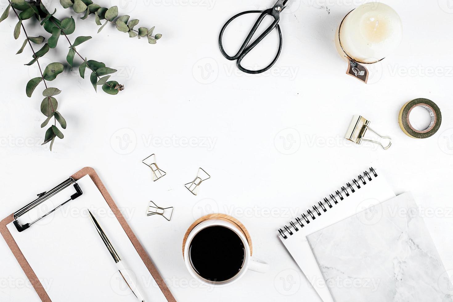 Workplace with eucalyptus, clipboard, notebook, cup of coffee, scissors, candle and pen. photo
