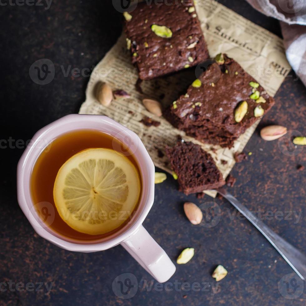 Tea with lemon and mint leaf with homemade biscuit brownie with pistachios for Breakfast on stone table background. Close-up, top view. copy space photo