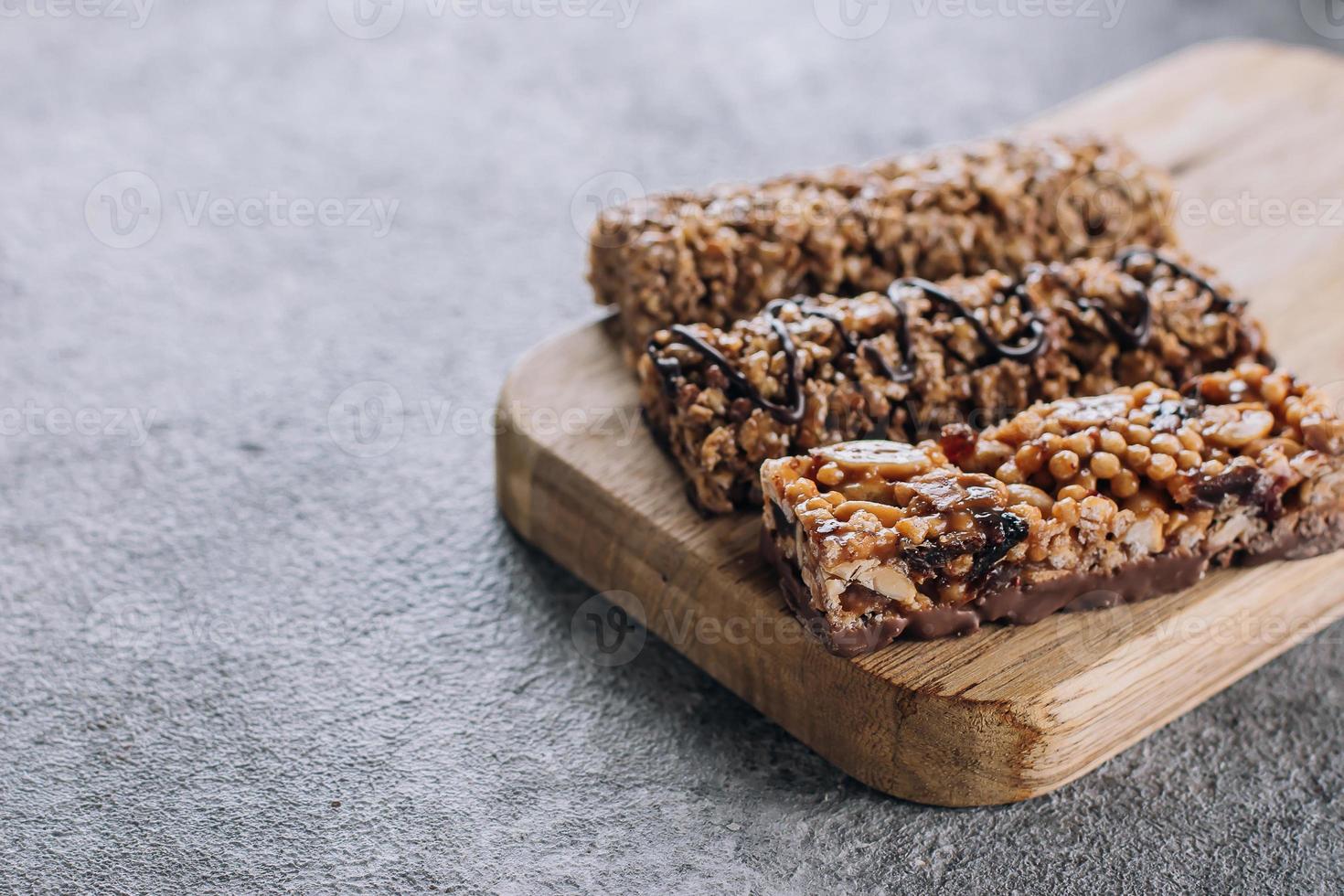 Healthy snack. Granola bar. Cereal granola bar with nuts, chocolate on wooden board. Concrete table background. Copy space photo