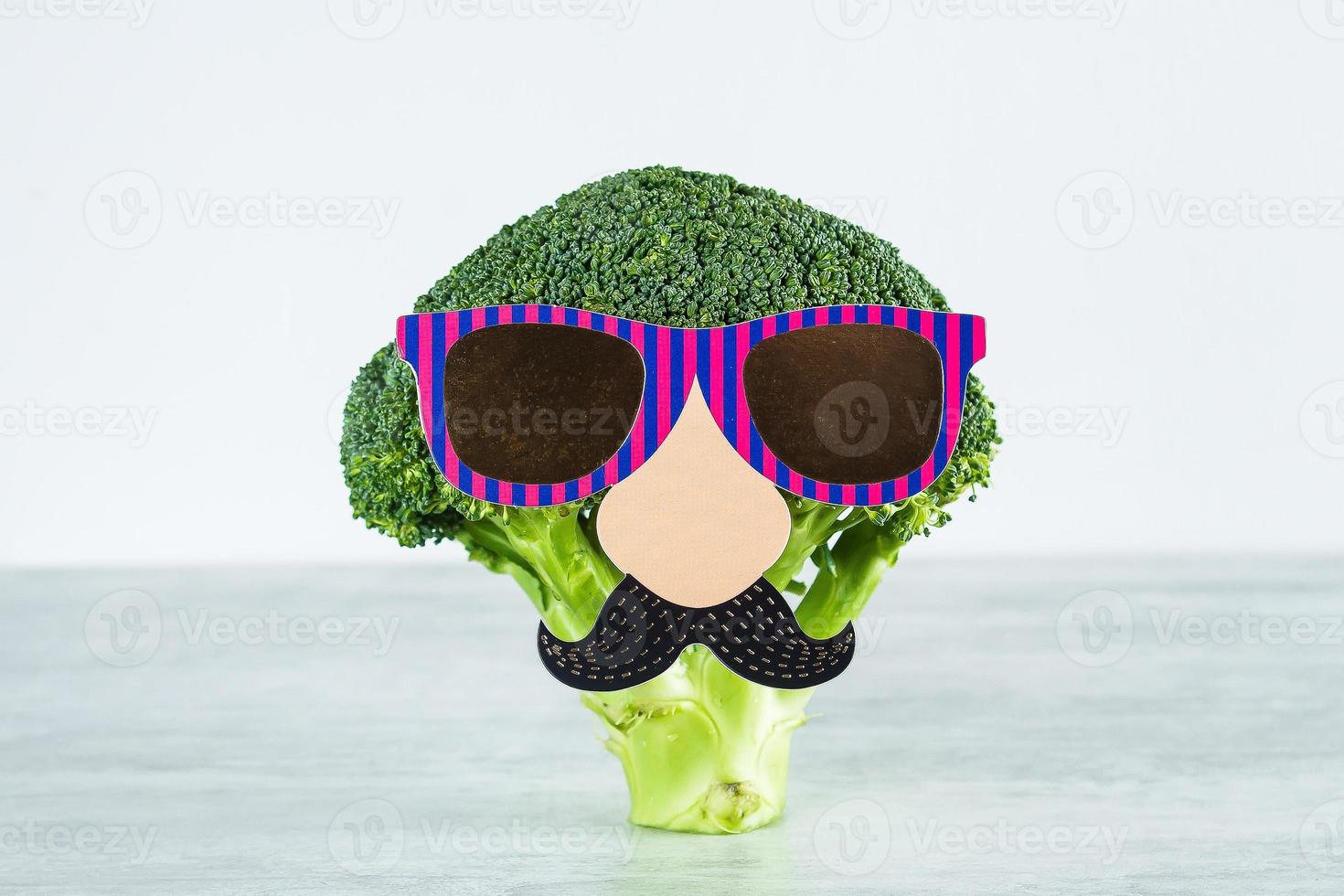 Funny cute vegetables broccoli. Broccoli with paper mustache and glasses. Healthy food concept photo