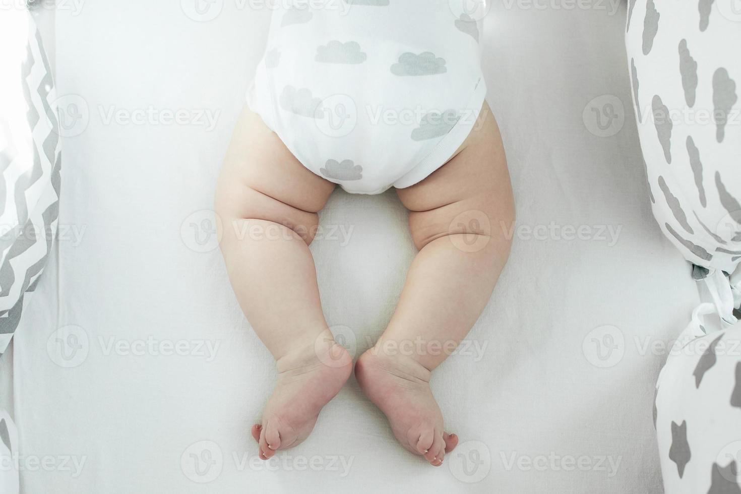 Newborn baby boy in white bodysuit with clouds in bed. New born child sleeping. Children sleep. photo