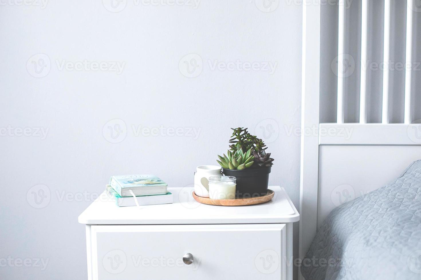 Tiny succulents, candles and books on bedside table in the bedroom in scandinavian style home photo