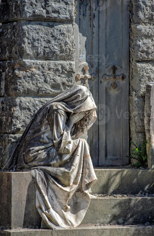 Widow while crying marble statue outside a tomb photo