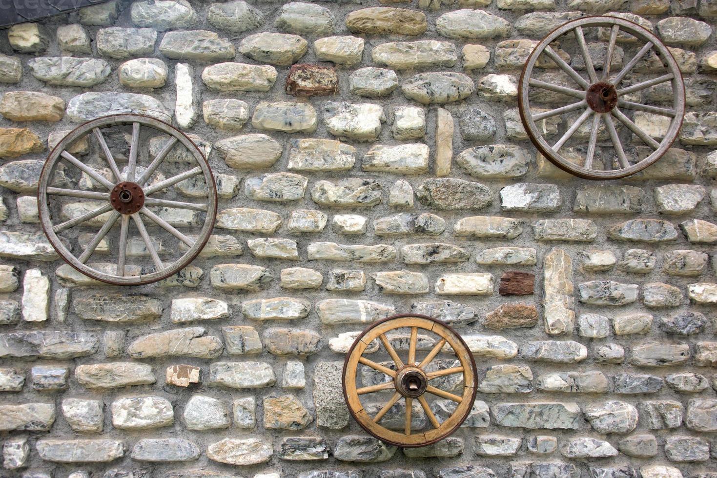 Far west wagon wheel on stone wall photo