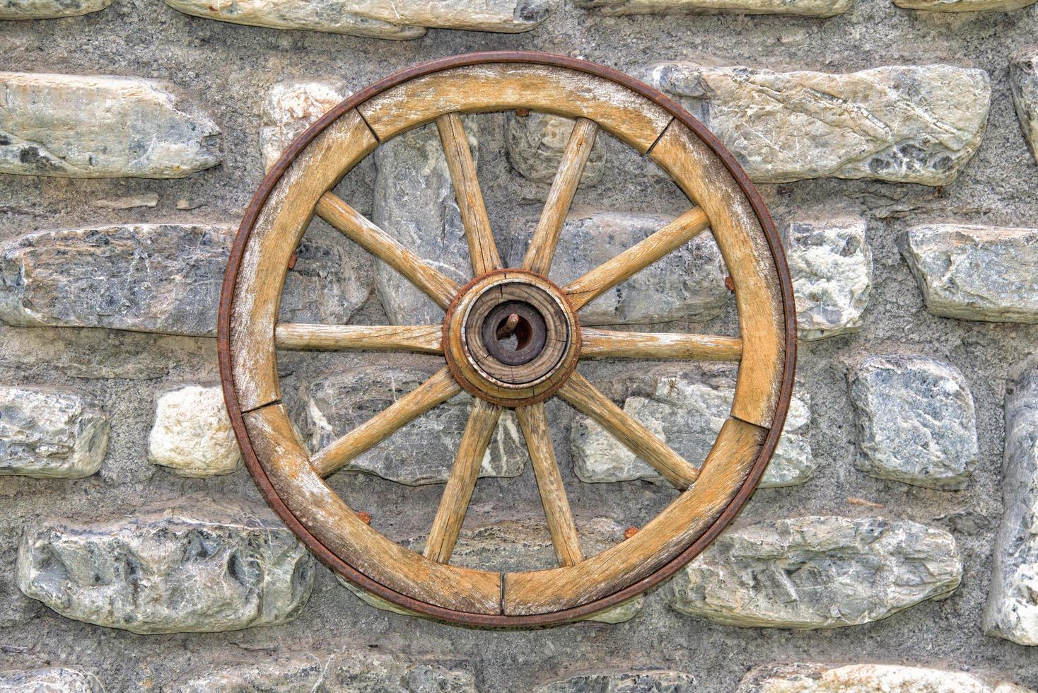 Far west wagon wheel on stone wall photo