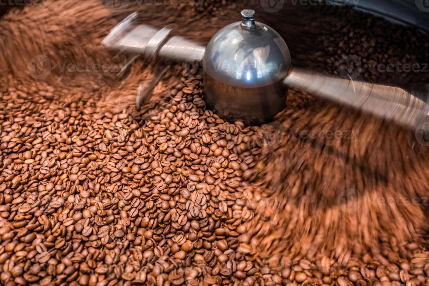 Máquinas profesionales de refrigeración giratoria asada y movimiento de granos de café marrones frescos cerca de la foto oscura en la fábrica, efecto de desenfoque de movimiento. Primer plano de tostado de semillas de café marrón fresco