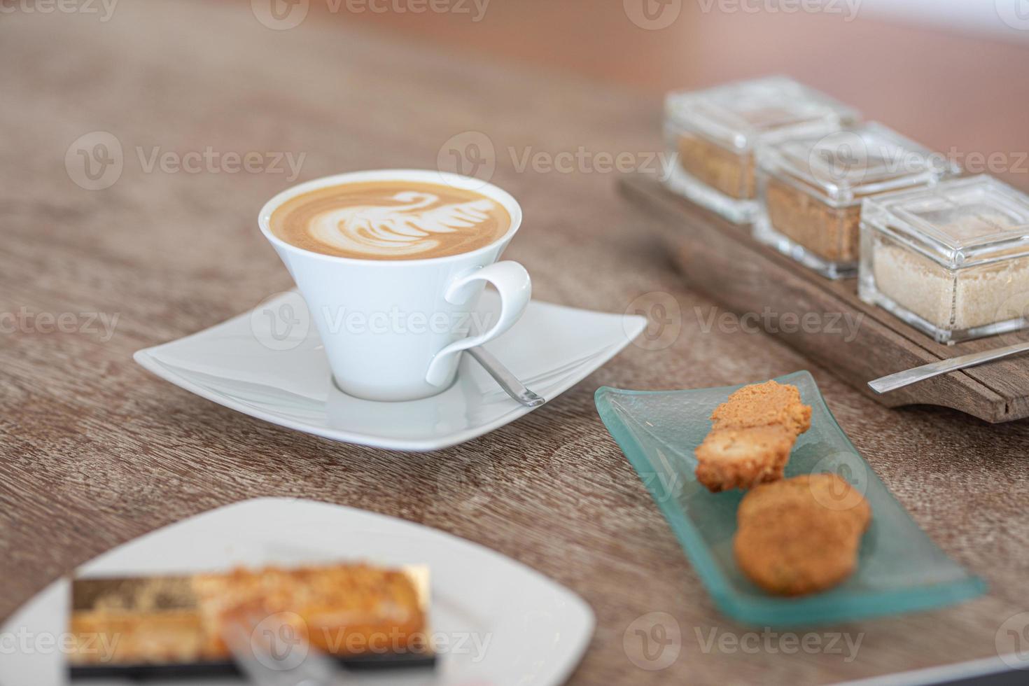 Coffee cup with chocolate cookie on bright wooden background. Cup of cappuccino coffee on wooden table. photo