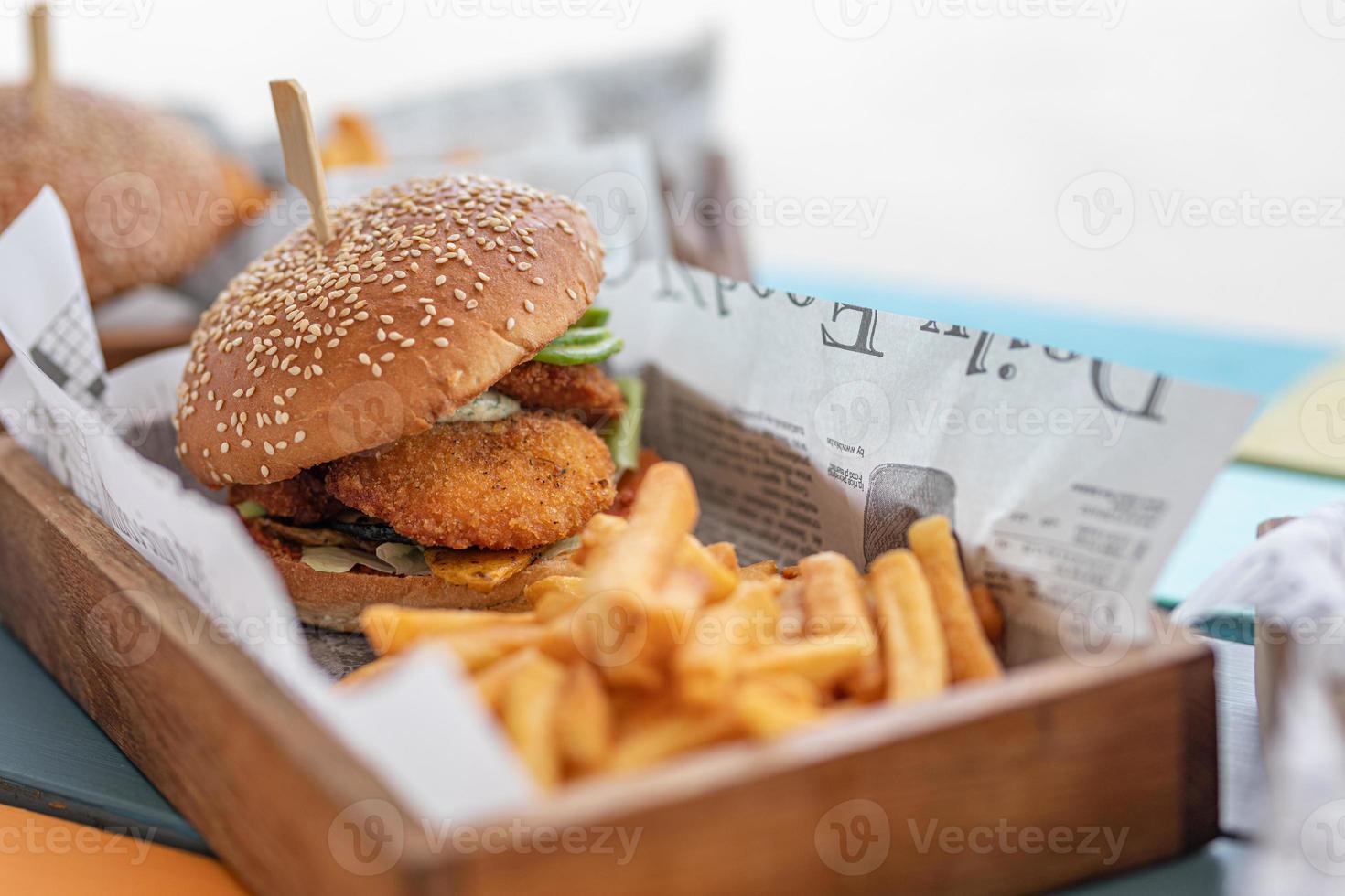 deliciosas hamburguesas caseras de ternera, queso y verduras patatas fritas en una vieja tabla de madera en el fondo borroso del restaurante al aire libre foto