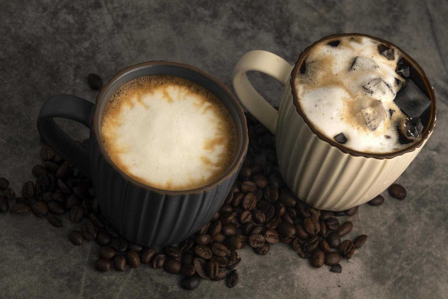 café con leche caliente y café con leche helado con granos de café sobre fondo de hormigón. foto