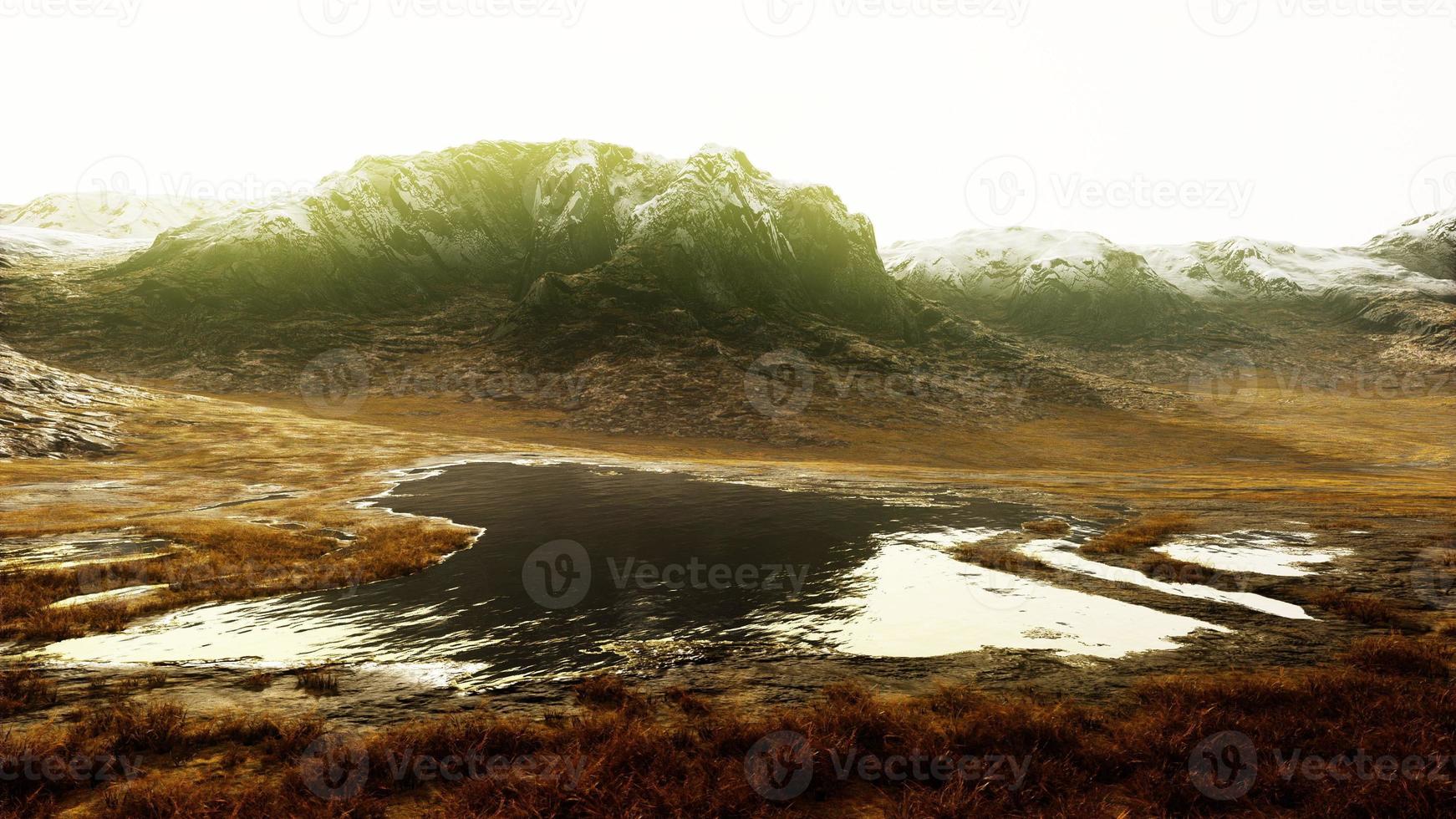 Plain with dried grass and mountain peaks in the background photo