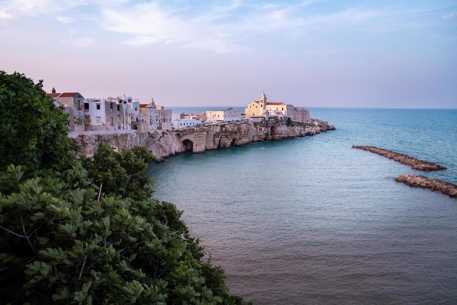 vista panorámica de la puesta de sol sobre el casco histórico y la iglesia de san francesco, vieste, gargano, apulia, italia foto