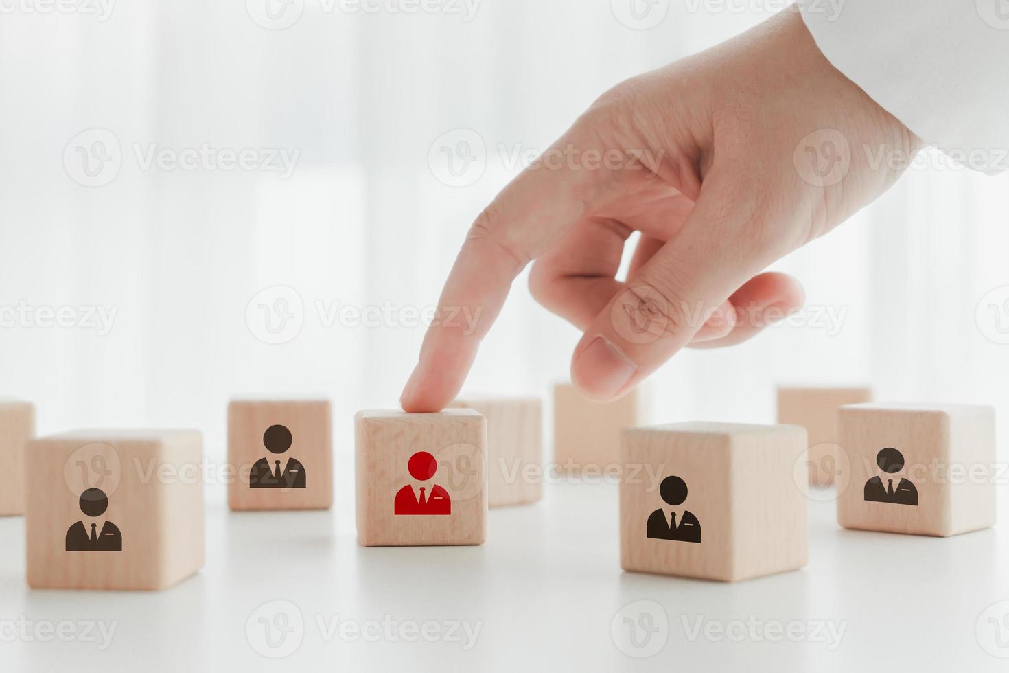 Hand point to red human icon on wooden block. Business hiring and recruitment selection. Career opportunity. Human Resource Management. Choice of new employee or leader from the crowd. photo