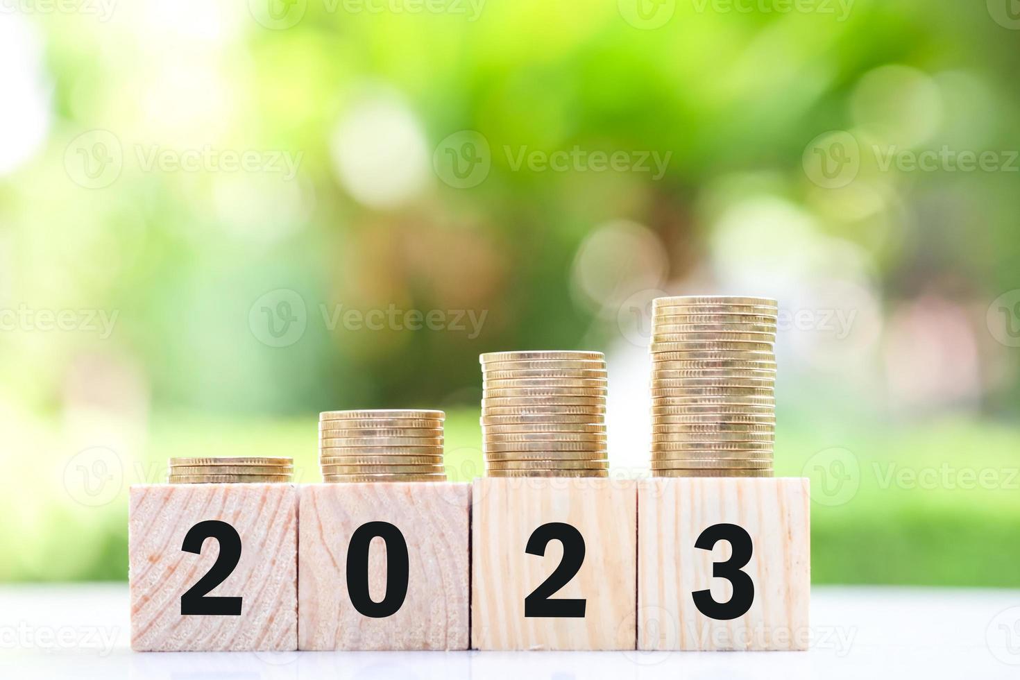 2023 objetivo y objetivo, negocios y ahorro de dinero. concepto de crecimiento financiero, aumento de la tasa de interés, inflación, precio de venta, préstamo, hipoteca y aumento de impuestos. paso de pila de monedas en bloques de madera número 2023. foto