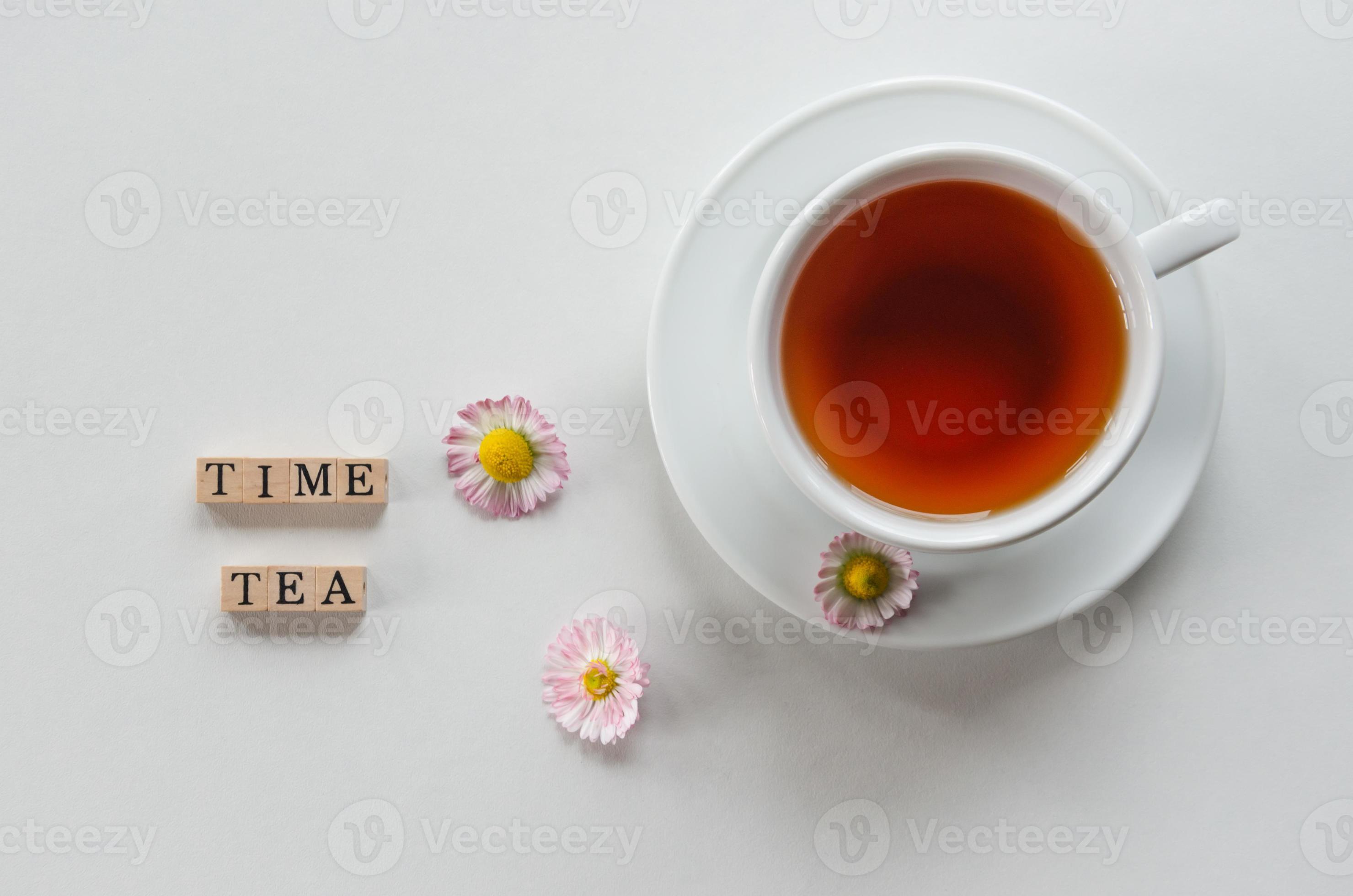 a cup of tea on a light background with flowers and letters tea time