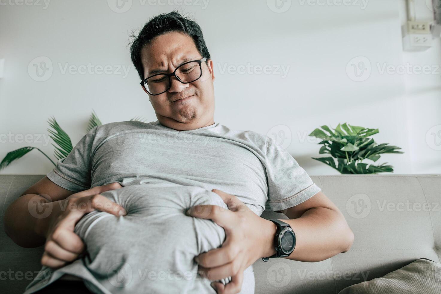 hombre gordo sentado en el sofá y muestra obesidad con estrés foto