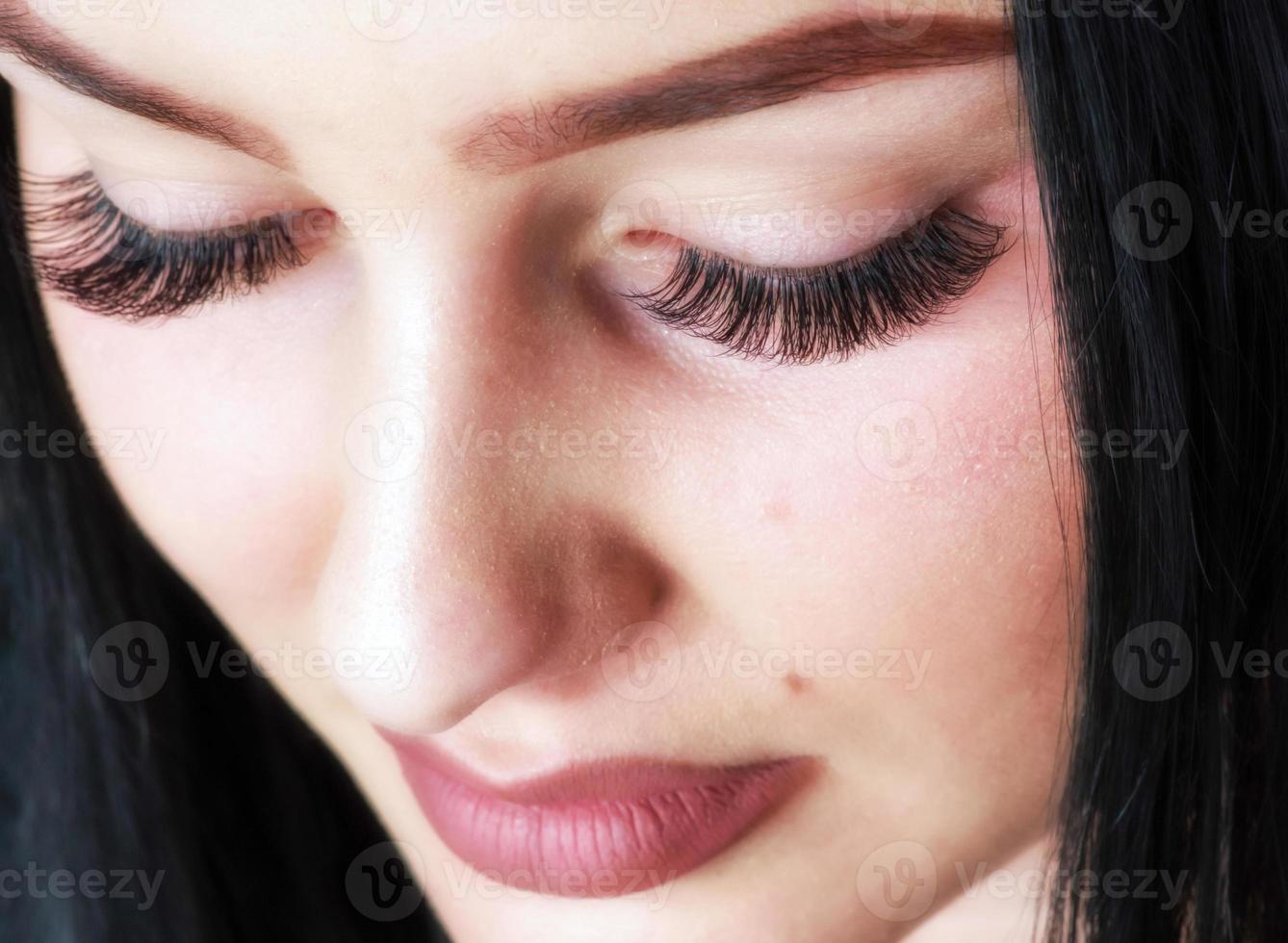 maquillaje de pestañas. cara de belleza de mujer con extensiones de pestañas negras foto
