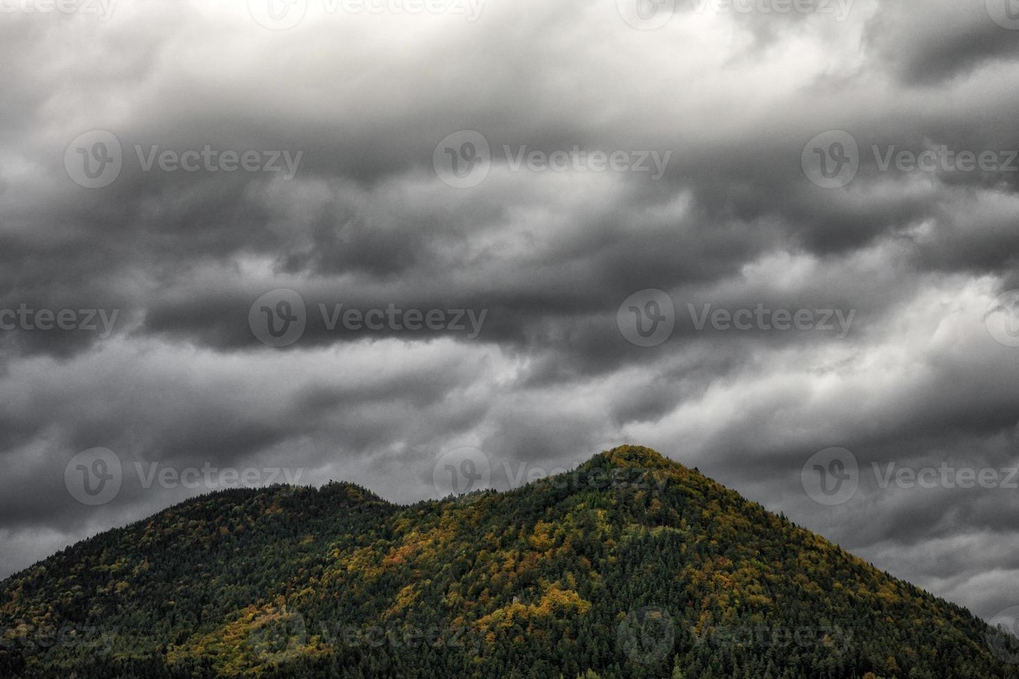 Dark stormy clouds over top of the hill photo