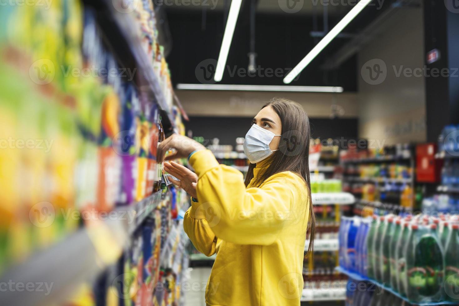 Woman wearing protective mask and buying food in grocery store during virus epidemic. young woman wearing a protective mask and gloves shopping in a time of virus pandemic, buying food supplies photo