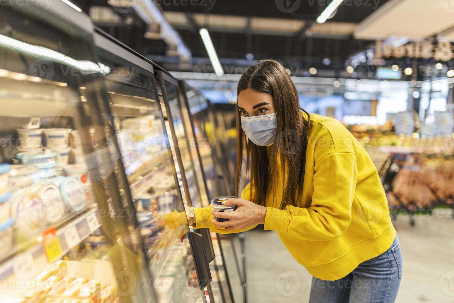 Young woman wearing disposable medical mask shopping in supermarket during coronavirus pneumonia outbreak. Protection and prevent measures while epidemic time. photo