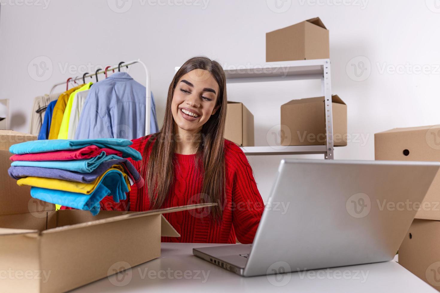 Woman packing item that she sells online. Working woman at online shop. She wearing casual clothing and checking on laptop address of customer and package information. small owner business photo