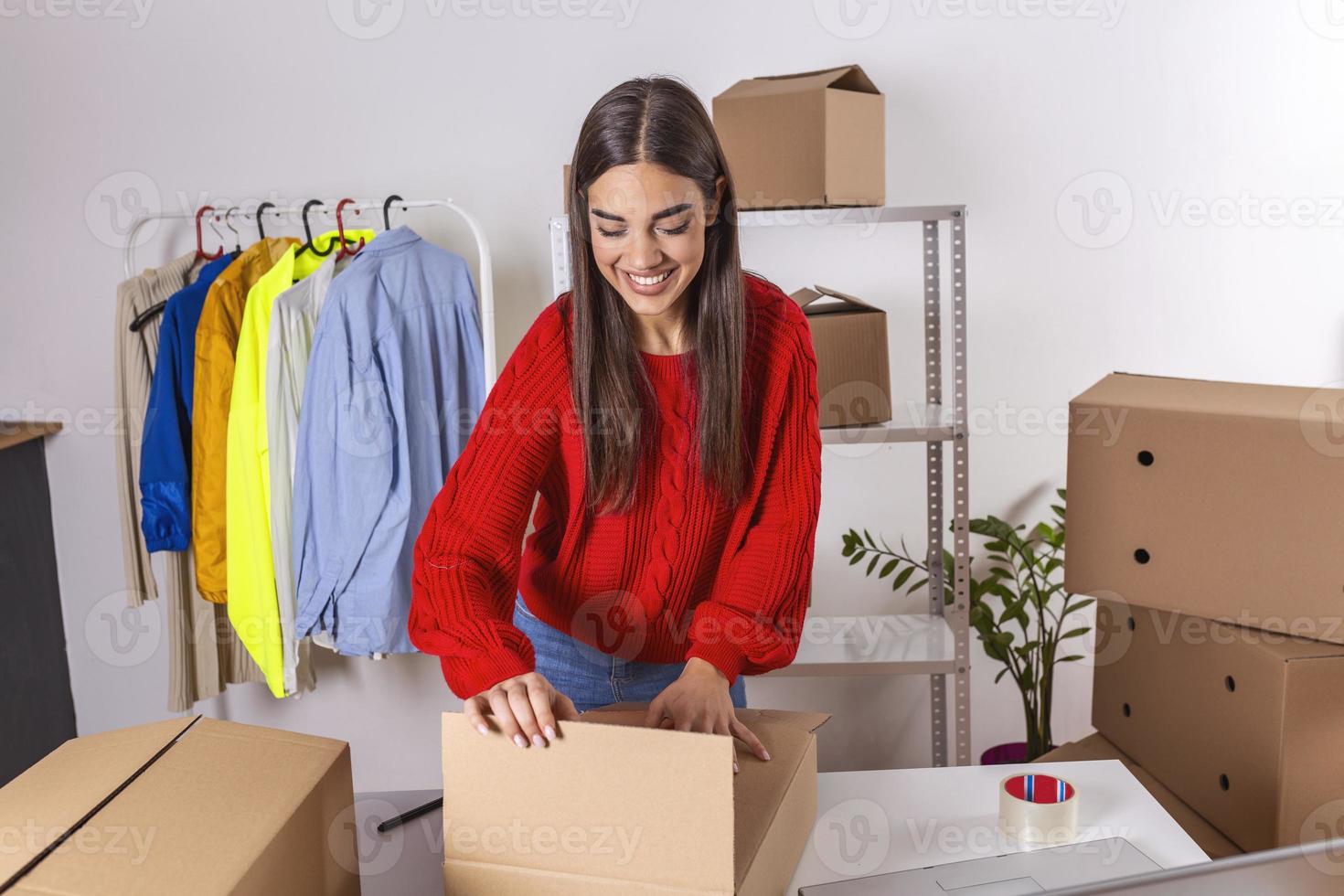 propietaria de una pequeña empresa de una tienda en línea. caja de embalaje del vendedor y preparación para la entrega. mujer joven que se siente feliz. embalaje de mercancías para su entrega al cliente. venta en línea foto