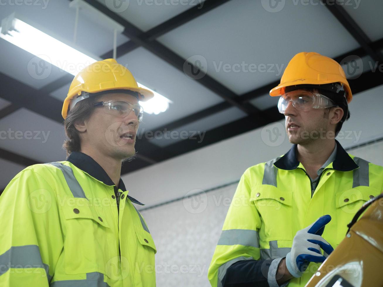 Factory indoor room engineer man manager person talk speak discussion staff employee labor male yellow hardhat helmet safety wear glasses work job occupation career supervisor electronic industry photo