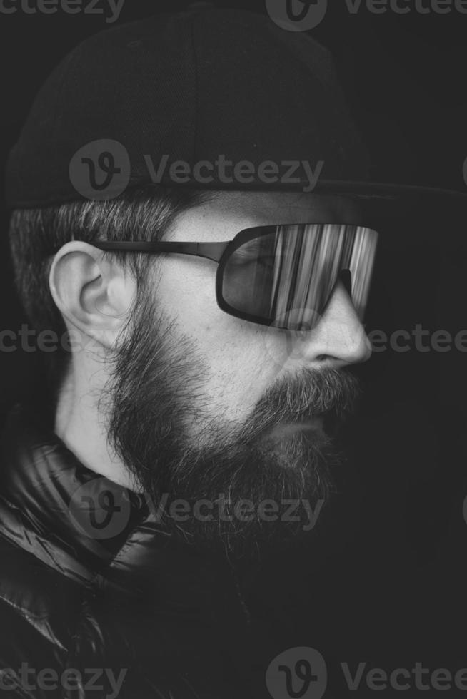 Flat and black portrait of young man with beard and sports glasses photo