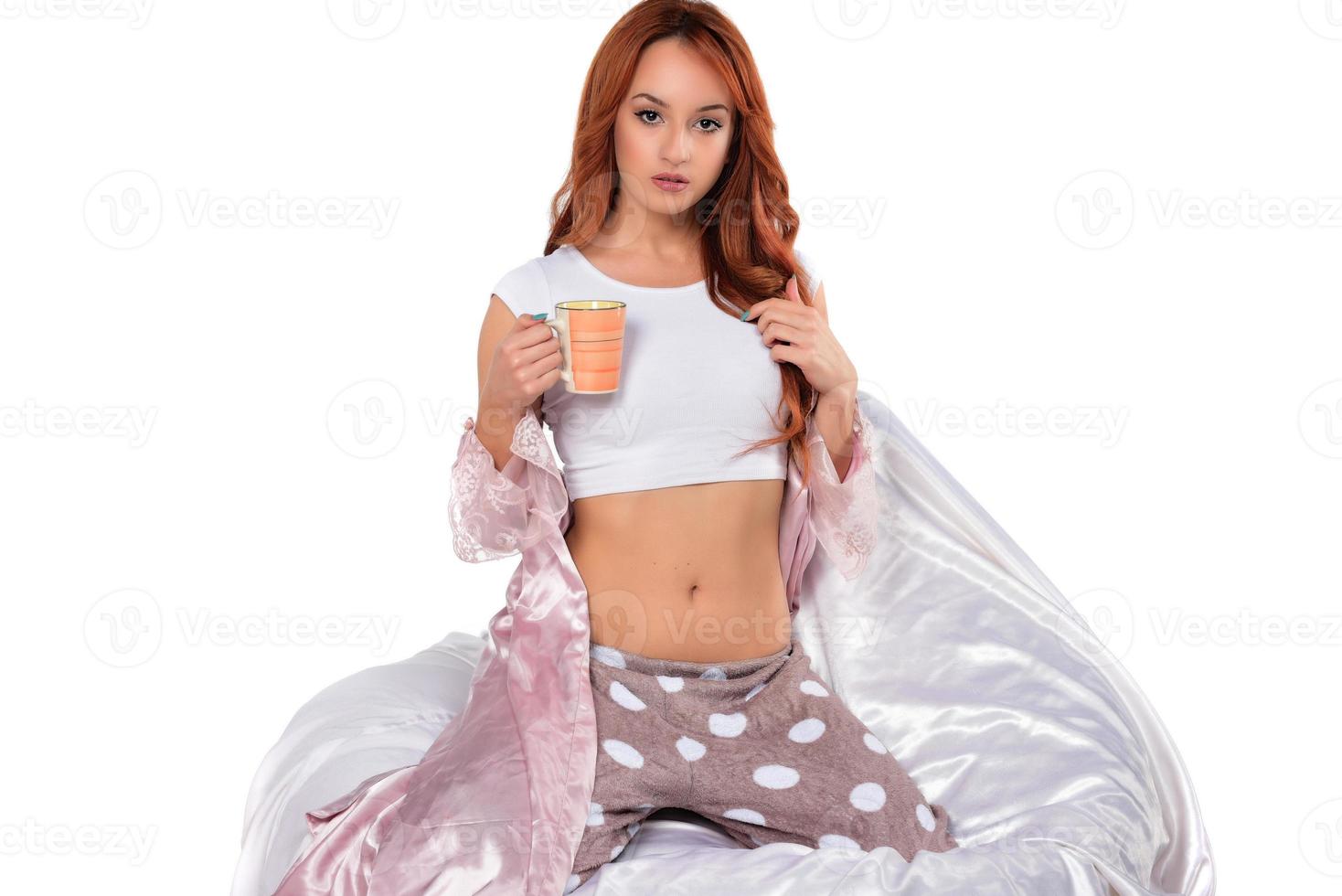 Young woman with cup of tea sitting on beanbag chair against white background photo