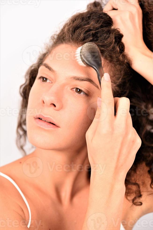 disfrutando de una mujer encantadora con un cepillo especial para una limpieza profunda del maquillaje facial foto