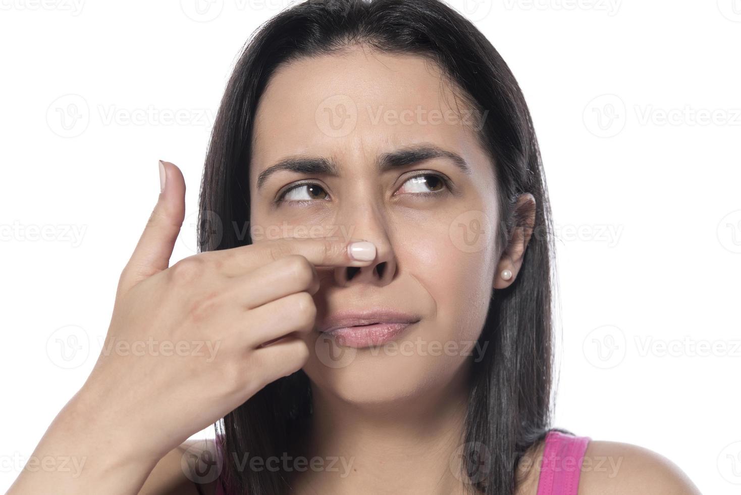 profile of young happy woman touches her nose with her finger on a white background photo