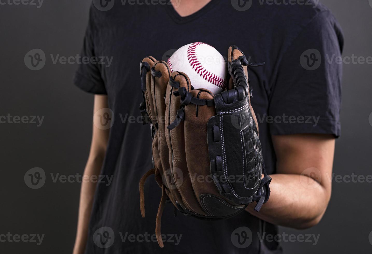 modelo masculino asiático con guante de béisbol aislado sobre fondo oscuro. concepto de jugador de béisbol foto