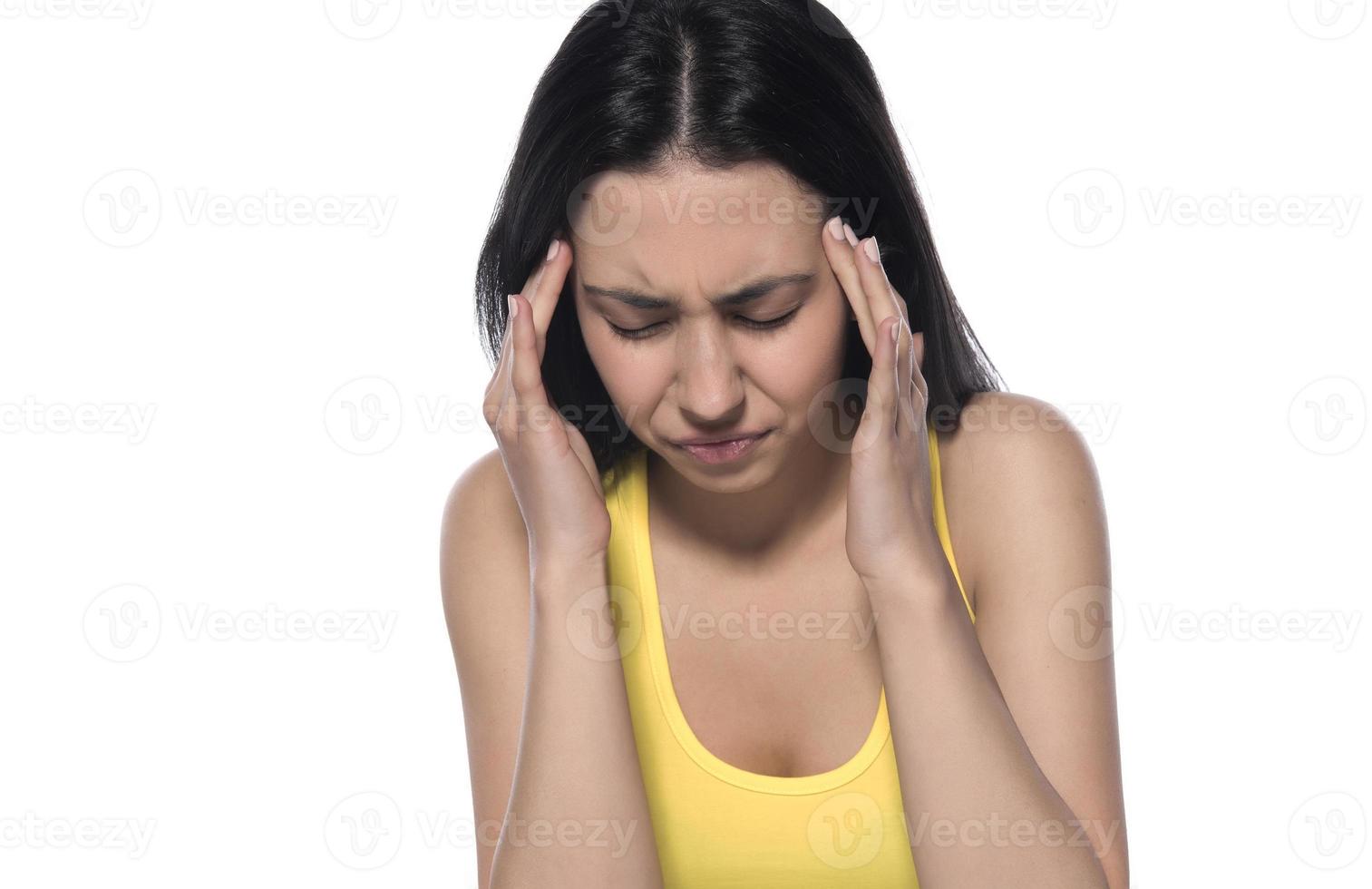 Young beautiful woman has headache, isolated on gray background. Exhausted girl portrait photo