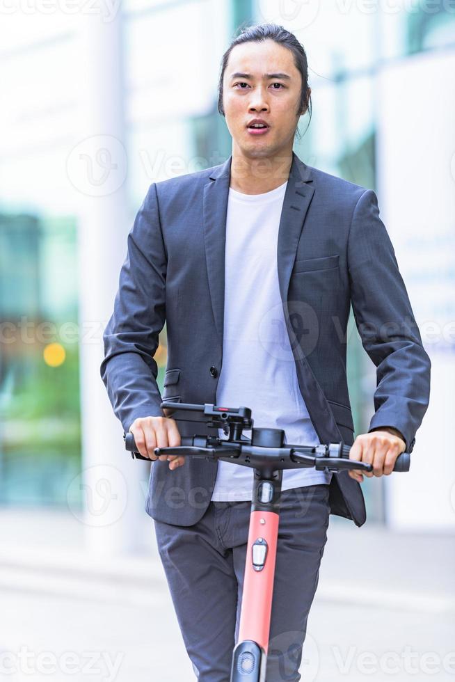 hombre de negocios asiático montando scooter eléctrico foto