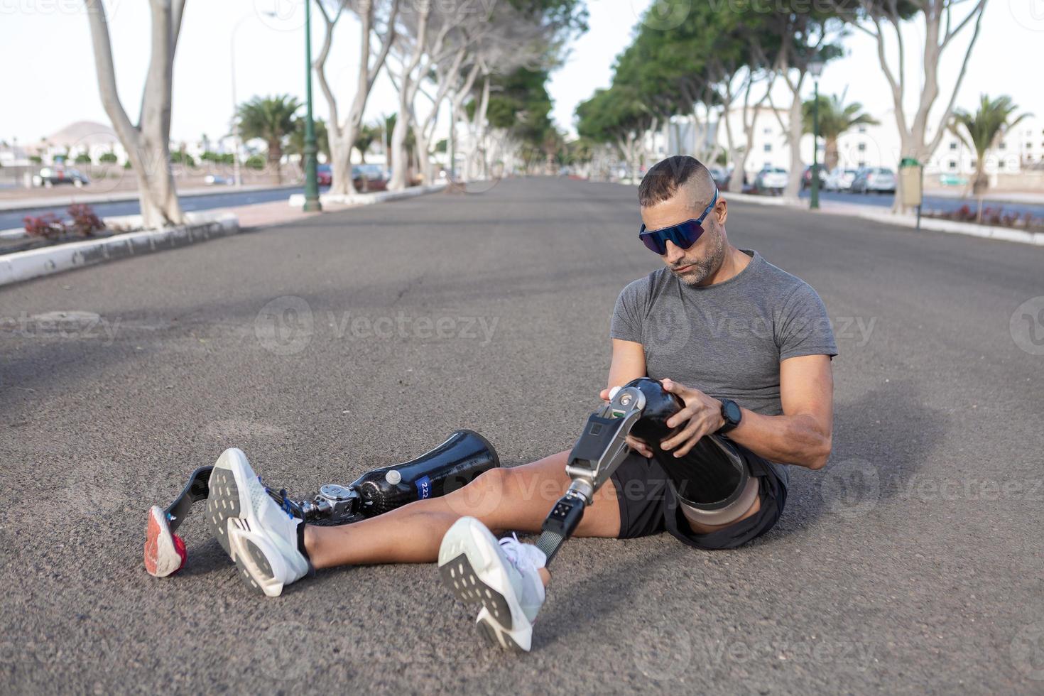 Young male amputee taking off artificial leg changing for running photo